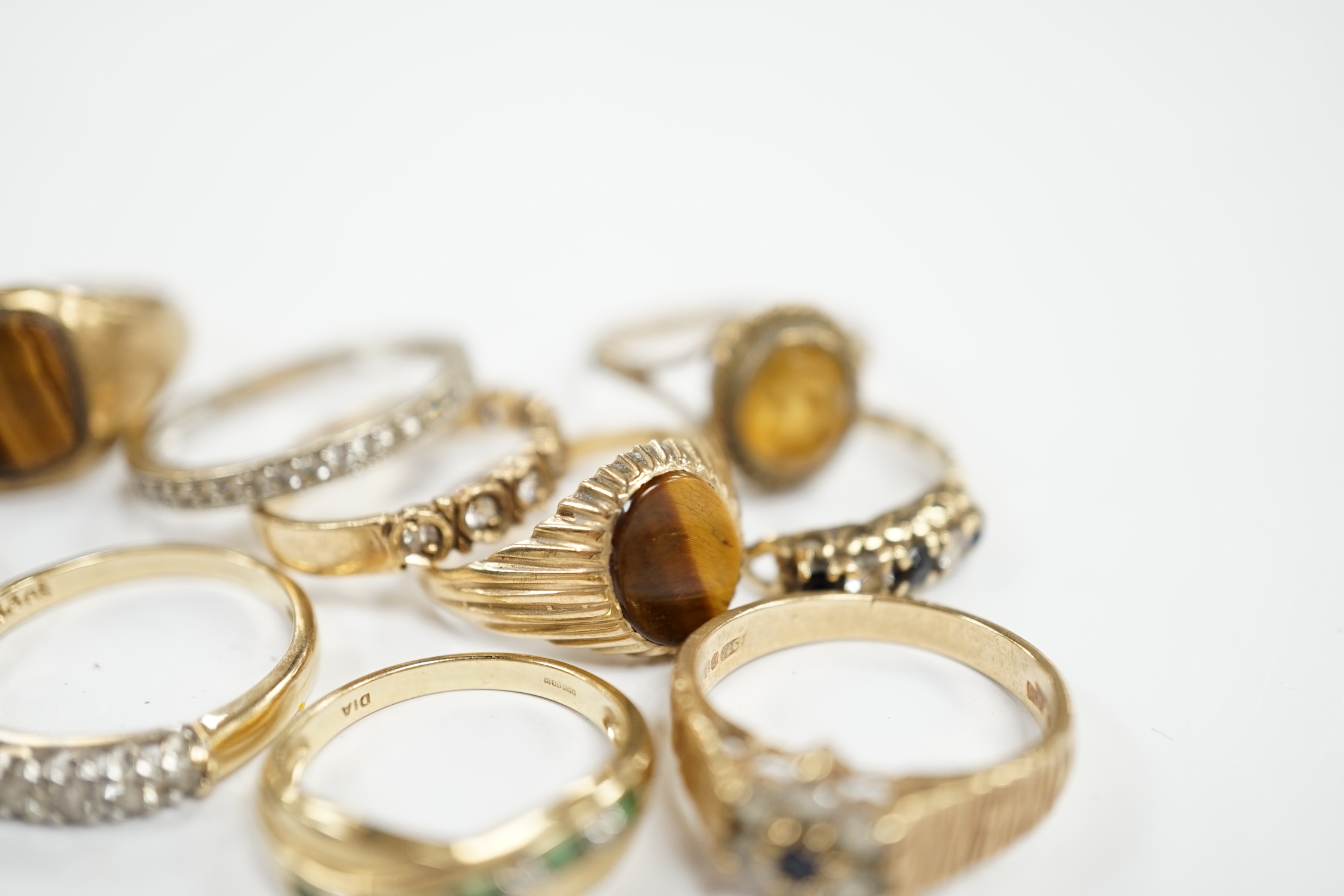 Ten assorted modern 9ct gold and mainly gem set rings, including two with tiger's eye quartz and a seven stone half hoop diamond set, size M/N, gross weight 25.5 grams. Condition - fair